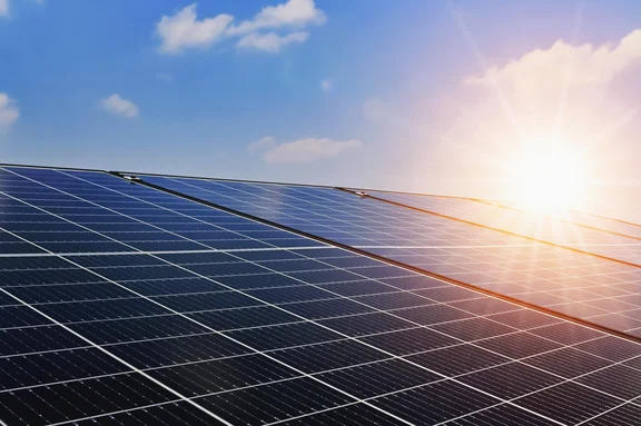 Solarmodule sind vor einem blauen Himmel mit Sonnenschein abgebildet.