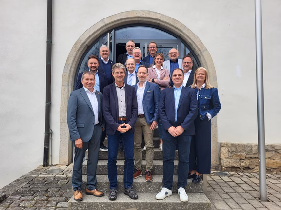 Regionalbeirat Mehrere Personen stehen in Gruppenanordnung auf einer Steintreppe vor einem Gebäude mit Rundbogen-Eingang und Glastür, aufgenommen bei einem Treffen des Regionalbeirats.
