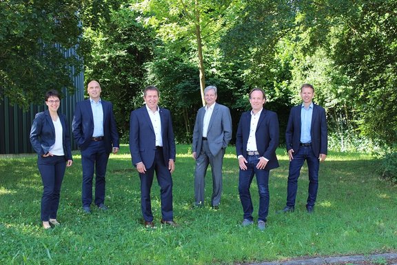 Gruppenbild der gesamten Geschäftsleitung auf grüner Wiese