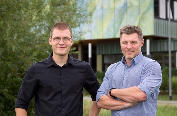 Zwei Energieberater stehen nebeneinander mit Stadtwerk-Gebäude im Hintergrund