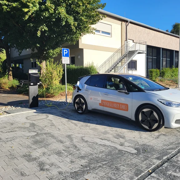 Öffentliche AC-Ladesäule mit zwei Ladepunkten in Althausen. Ein Elektrofahrzeug der Stadtwerk Tauberfranken lädt auf dem neu gestalteten Parkplatz.