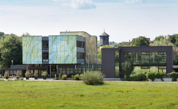 Farblich Grün-Blau integriertes Gebäude in die Landschaft