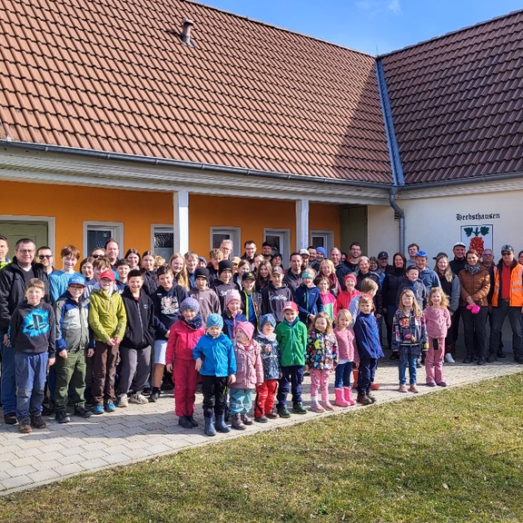 Kehrtwende-Aktion Viele Personen von jung bis alt stehen vor einem Gebäude und lächeln in die Kamera. Die Sonne scheint.