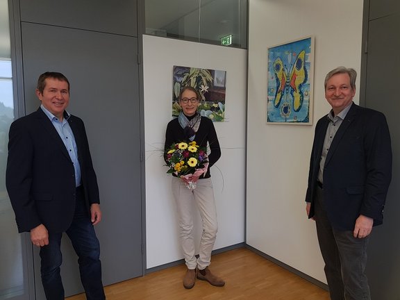 Mitarbeiterin erhält Blumenstrauß von beiden Geschäftsführern