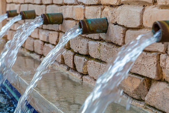 Wasser kommt durch mehrere Rohre aus einer gemauerten Wand
